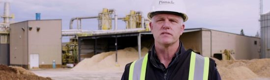 Person in front of wood pellet mill looking at the camera